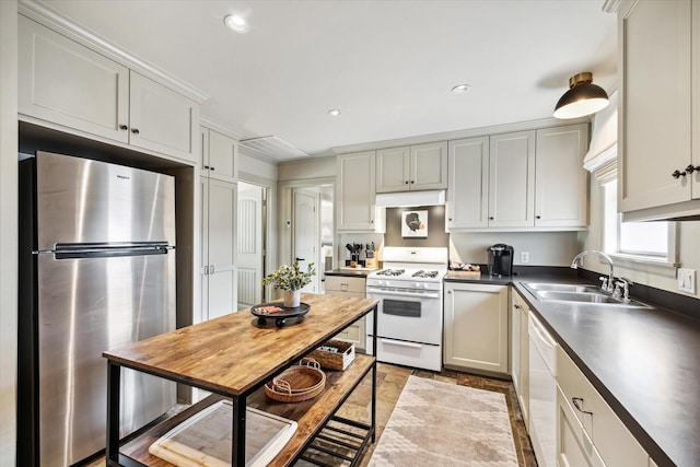 kitchen with dark countertops, white appliances, under cabinet range hood, and a sink