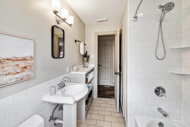 bathroom featuring visible vents, toilet, tile patterned flooring, shower / bathtub combination, and a sink