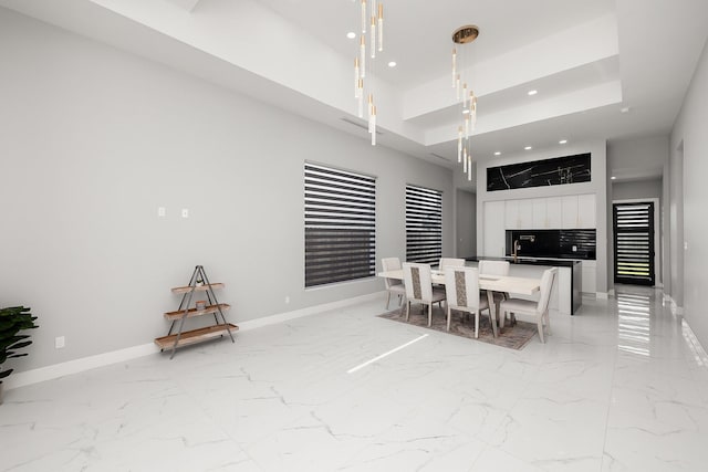 dining space with marble finish floor, a tray ceiling, recessed lighting, and baseboards