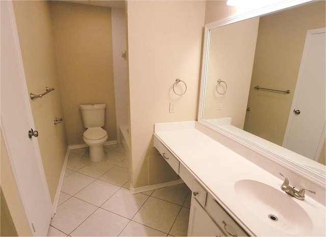 bathroom with tile patterned flooring, toilet, vanity, baseboards, and a tub