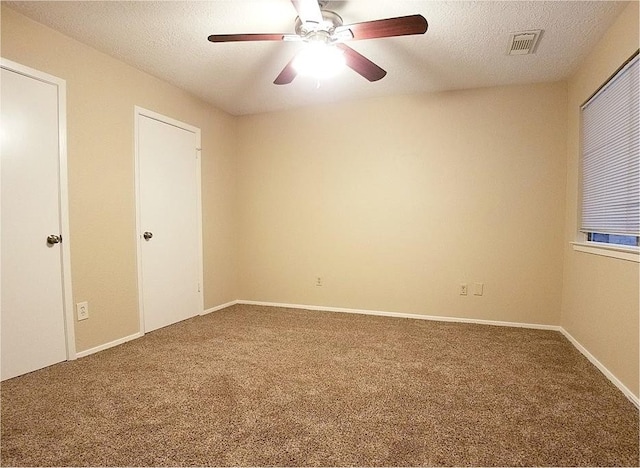 carpeted empty room featuring a textured ceiling, baseboards, visible vents, and a ceiling fan