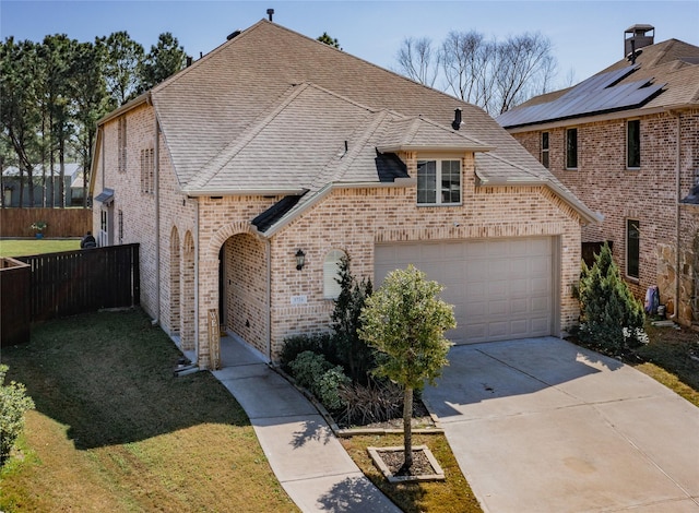 french country home featuring brick siding, fence, a front yard, a garage, and driveway