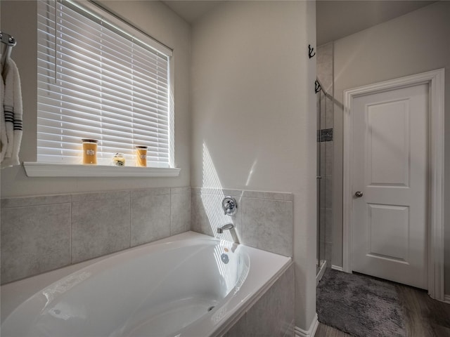 bathroom with a stall shower and a garden tub