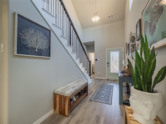 foyer with stairs, a high ceiling, wood finished floors, and baseboards