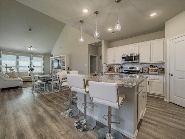 kitchen featuring dark wood-type flooring, light stone countertops, open floor plan, white cabinets, and stainless steel appliances