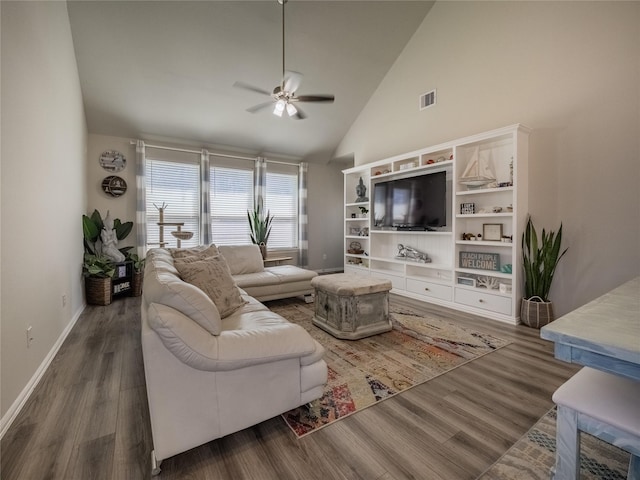 living area featuring visible vents, baseboards, ceiling fan, wood finished floors, and high vaulted ceiling