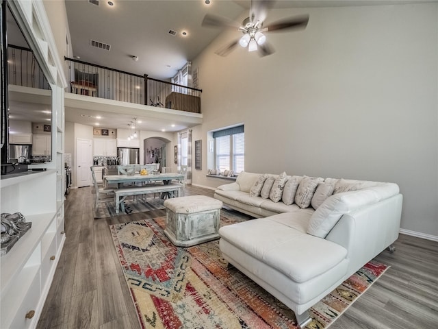 living room featuring a ceiling fan, wood finished floors, visible vents, and arched walkways