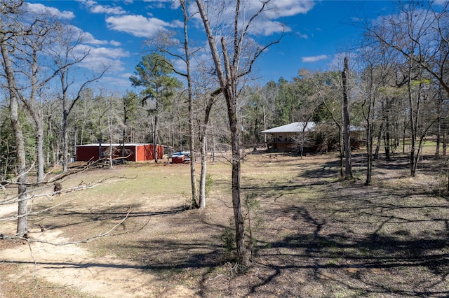 view of yard featuring a wooded view and an outbuilding