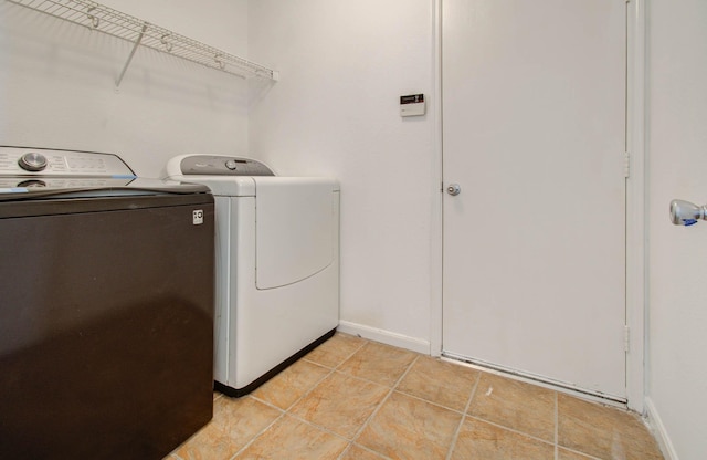 washroom with laundry area, baseboards, washing machine and clothes dryer, and light tile patterned floors