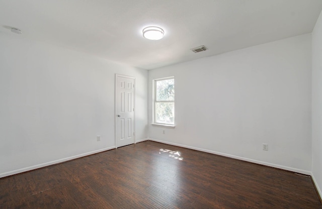 unfurnished room with baseboards, visible vents, and dark wood-type flooring