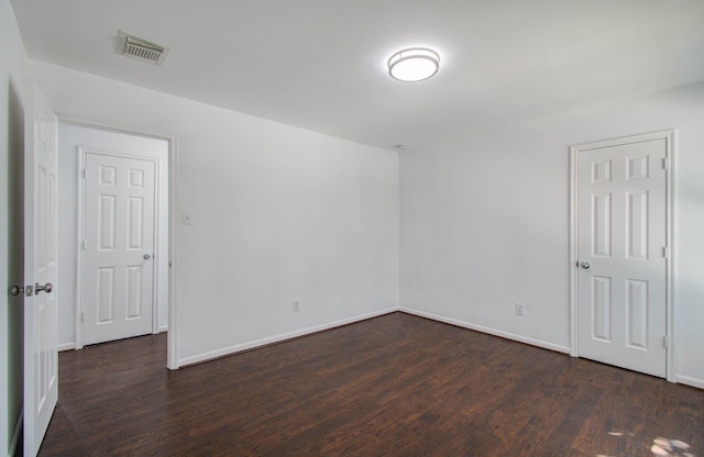 spare room with baseboards, visible vents, and wood finished floors