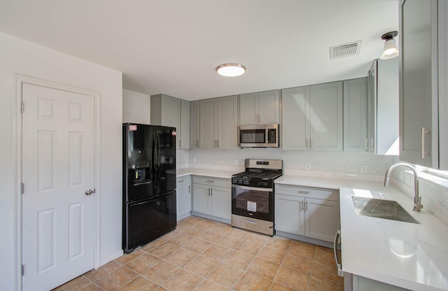 kitchen with appliances with stainless steel finishes, visible vents, a sink, and gray cabinetry