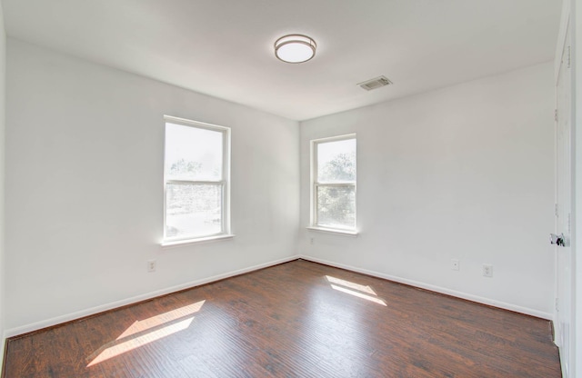 unfurnished room featuring visible vents, baseboards, and wood finished floors