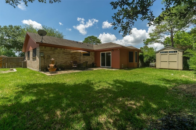 back of property with an outbuilding, a storage unit, a lawn, and fence