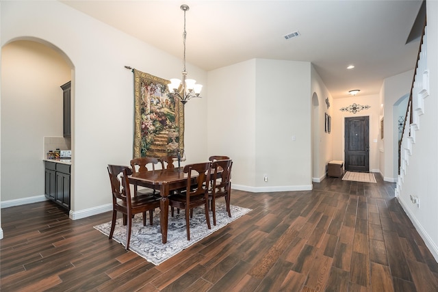 dining area with baseboards, visible vents, arched walkways, dark wood-style flooring, and an inviting chandelier