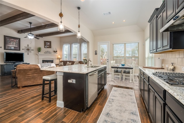 kitchen featuring appliances with stainless steel finishes, wood tiled floor, wall chimney range hood, a fireplace, and a sink