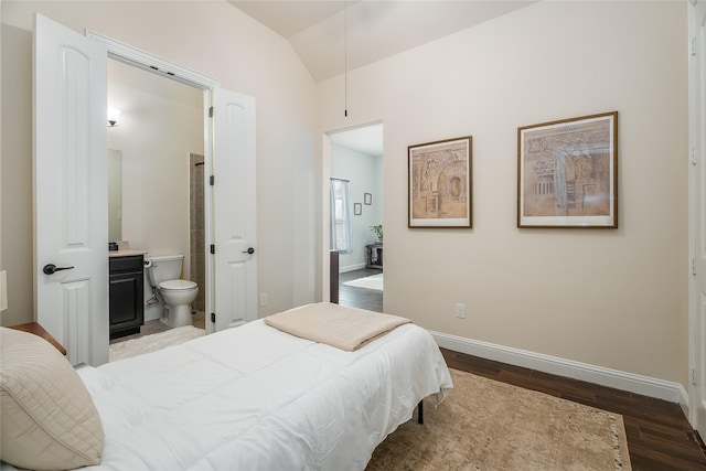 bedroom with lofted ceiling, dark wood-type flooring, ensuite bath, and baseboards