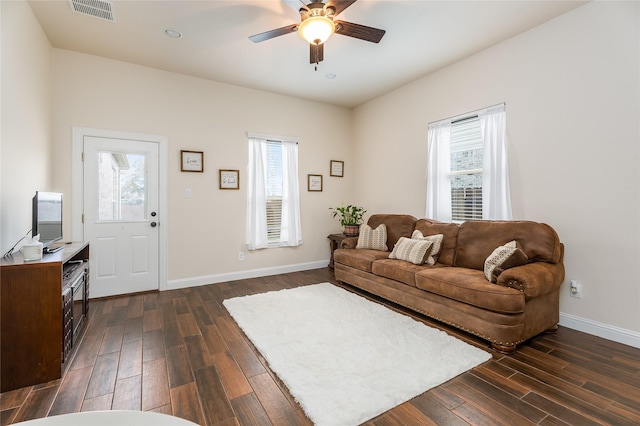 living room with dark wood-style flooring, visible vents, plenty of natural light, and baseboards