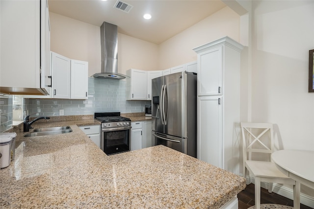 kitchen with visible vents, backsplash, appliances with stainless steel finishes, a sink, and wall chimney exhaust hood