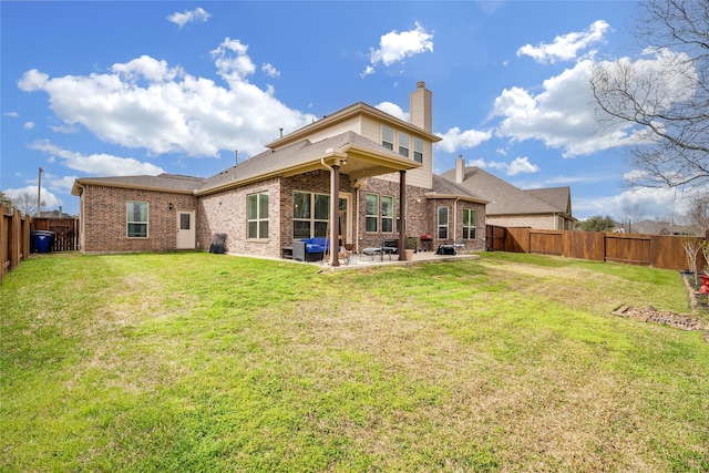 rear view of house with brick siding, a patio, and a fenced backyard