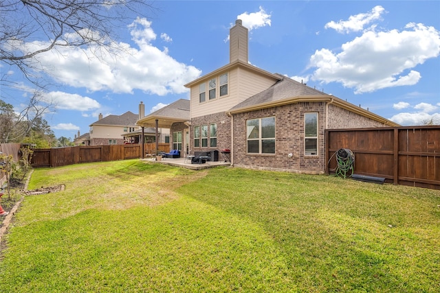 back of property with a yard, a fenced backyard, a patio, and brick siding