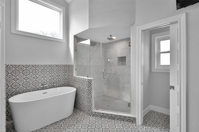 bathroom featuring a stall shower, a freestanding tub, wainscoting, and tile walls