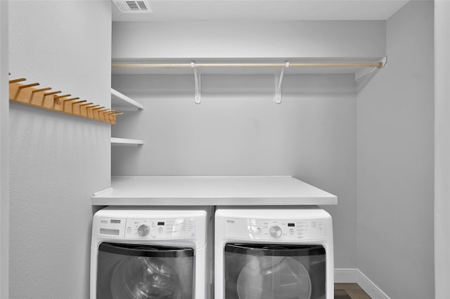 clothes washing area with laundry area, washing machine and clothes dryer, visible vents, and baseboards