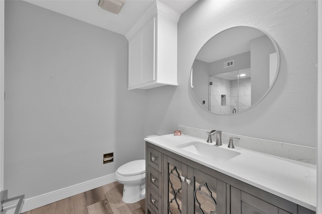 bathroom with visible vents, baseboards, toilet, wood finished floors, and vanity