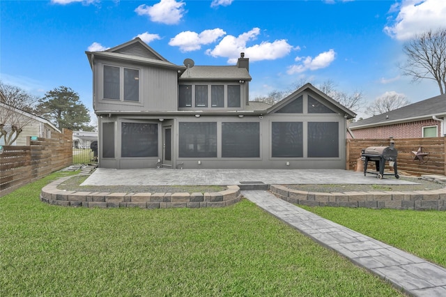 back of house with a fenced backyard, a patio, a chimney, and a lawn