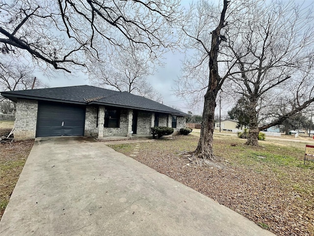 view of front facade with brick siding, concrete driveway, an attached garage, and a shingled roof