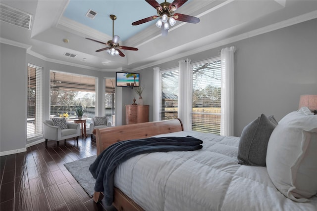 bedroom featuring dark wood finished floors, ornamental molding, a raised ceiling, and visible vents