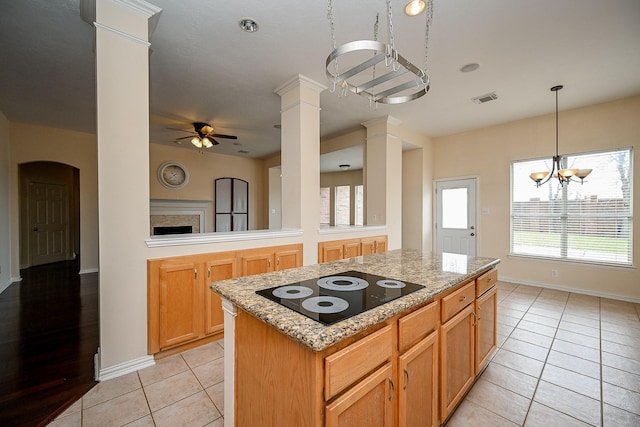 kitchen featuring decorative columns, light tile patterned floors, visible vents, a kitchen island, and black electric cooktop