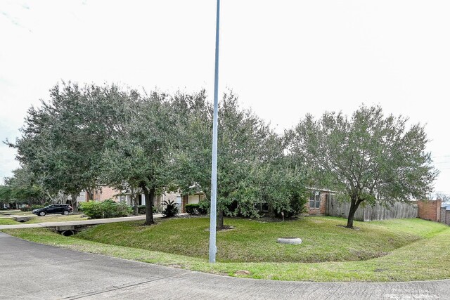 obstructed view of property with driveway, an attached garage, fence, a front lawn, and brick siding