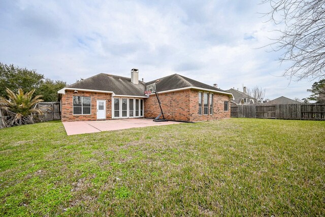 rear view of house with brick siding, a chimney, a patio area, and a fenced backyard