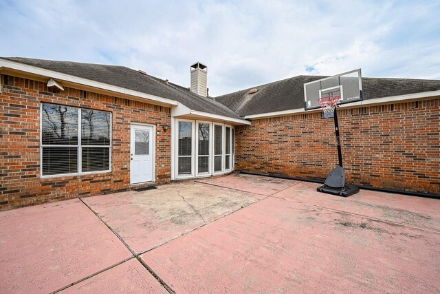 rear view of property featuring a patio, brick siding, and a chimney