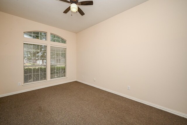 unfurnished room featuring a ceiling fan, dark carpet, and baseboards