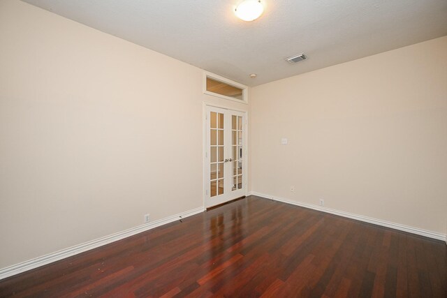 unfurnished room featuring baseboards, visible vents, dark wood-style flooring, and french doors