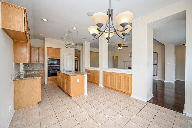 kitchen with light tile patterned flooring, a sink, backsplash, a center island, and black appliances