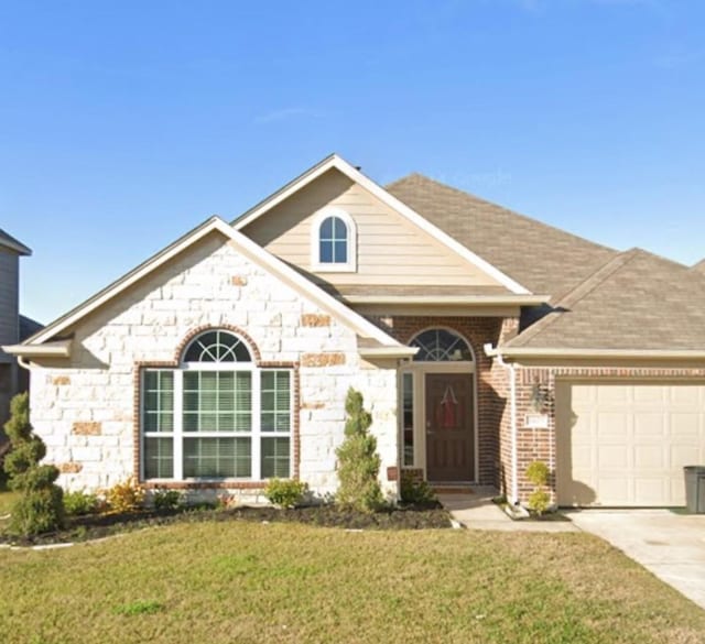 view of front of home with a garage, a shingled roof, concrete driveway, stone siding, and a front lawn