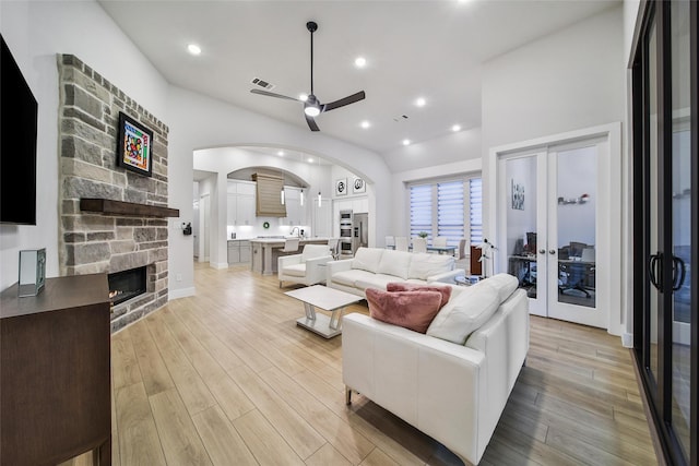 living room with light wood-style floors, arched walkways, visible vents, and a fireplace