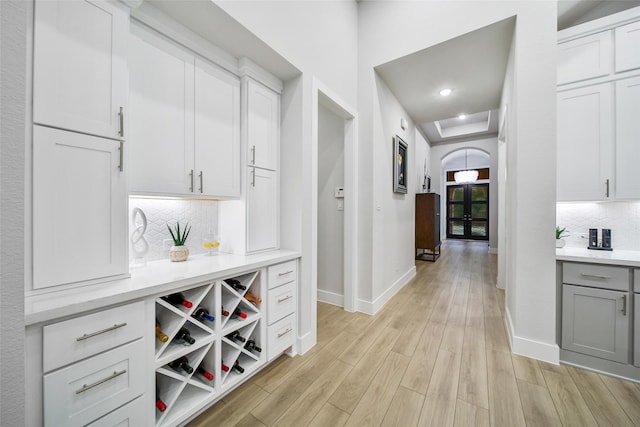 bar with arched walkways, recessed lighting, baseboards, light wood-type flooring, and backsplash