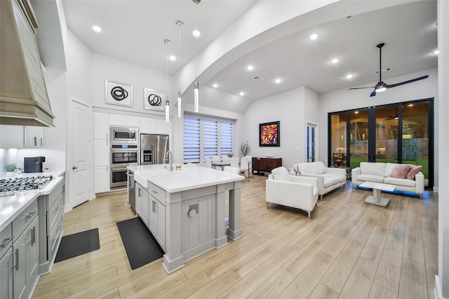 kitchen featuring light countertops, appliances with stainless steel finishes, light wood-type flooring, and custom range hood