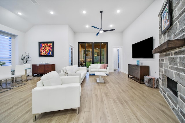 living room featuring ceiling fan, high vaulted ceiling, a stone fireplace, recessed lighting, and light wood finished floors