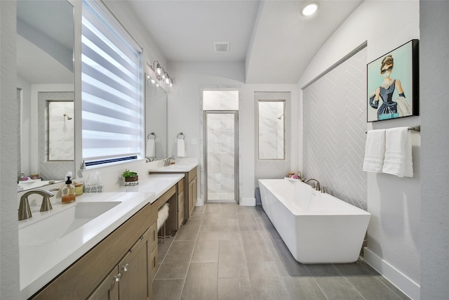 full bath with a stall shower, a soaking tub, a sink, and double vanity