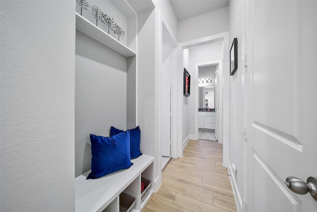 mudroom with a textured wall, light wood-type flooring, and baseboards