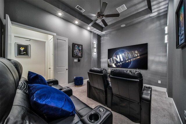 cinema with carpet floors, a tray ceiling, and visible vents