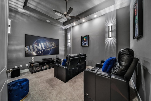 home theater with carpet floors, a tray ceiling, a ceiling fan, and baseboards