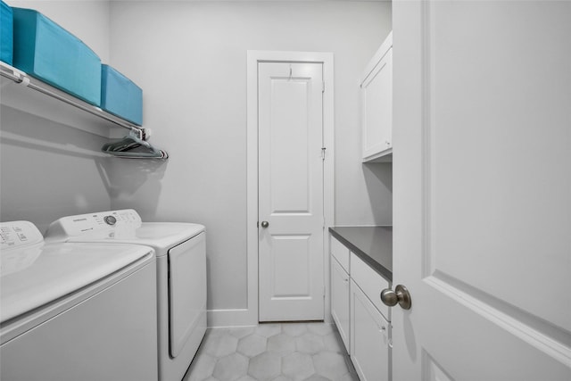 laundry room featuring light tile patterned floors, separate washer and dryer, cabinet space, and baseboards