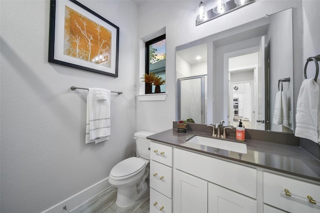 full bathroom with toilet, wood finished floors, vanity, baseboards, and a stall shower