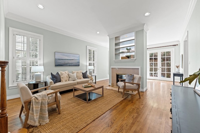 living room featuring recessed lighting, light wood-style flooring, ornamental molding, and a high end fireplace